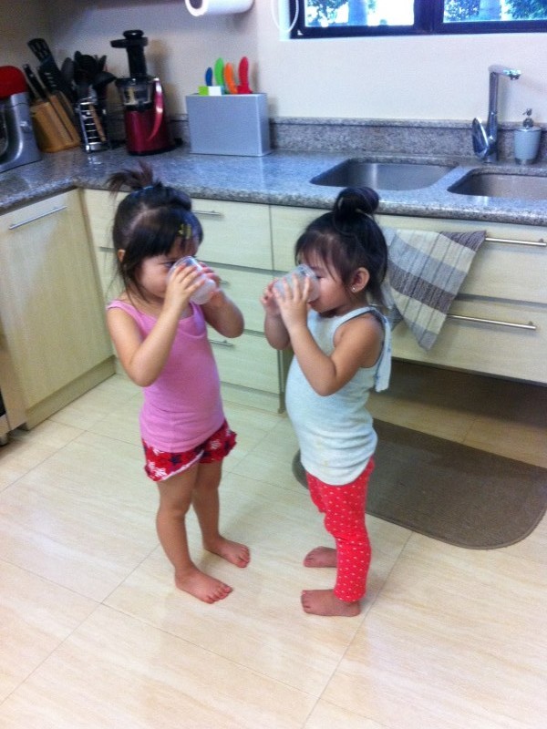 Alba and Rielle at 3 drinking water in the kitchen