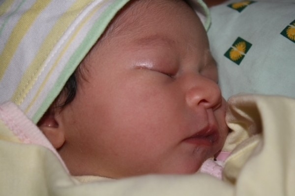 The first photo of Alba only hours old, she is in a yellow blanket wearing a yellow hat
