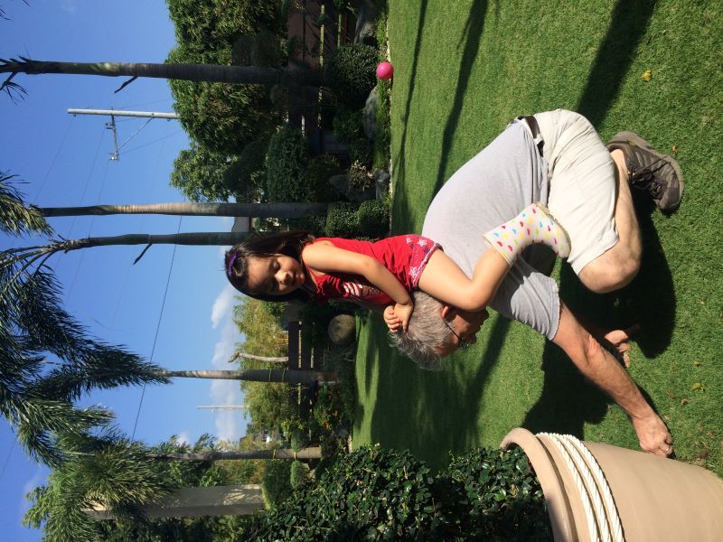 Alba sitting on David's bck while he weeds